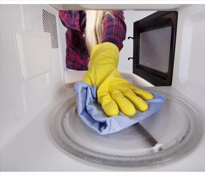 Closeup of hand in protective glove wiping rag microwave. View from the interior of the oven