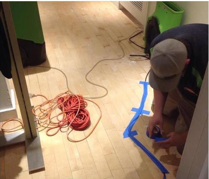 A specialist is checking a floor after a water loss